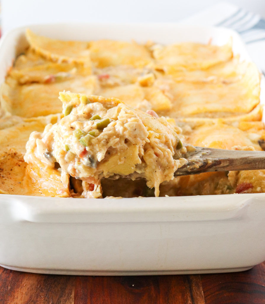 a wooden spoon scooping a slice of king ranch chicken casserole