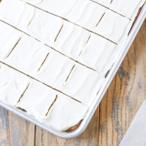 half sheet pan of banana bars sliced and topped with cream cheese frosting