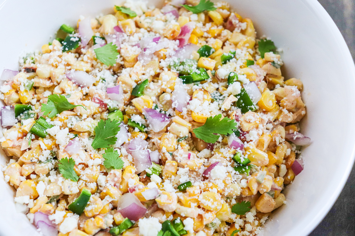 bowl of prepared Mexican corn salad with visible cilantro and cotija cheese