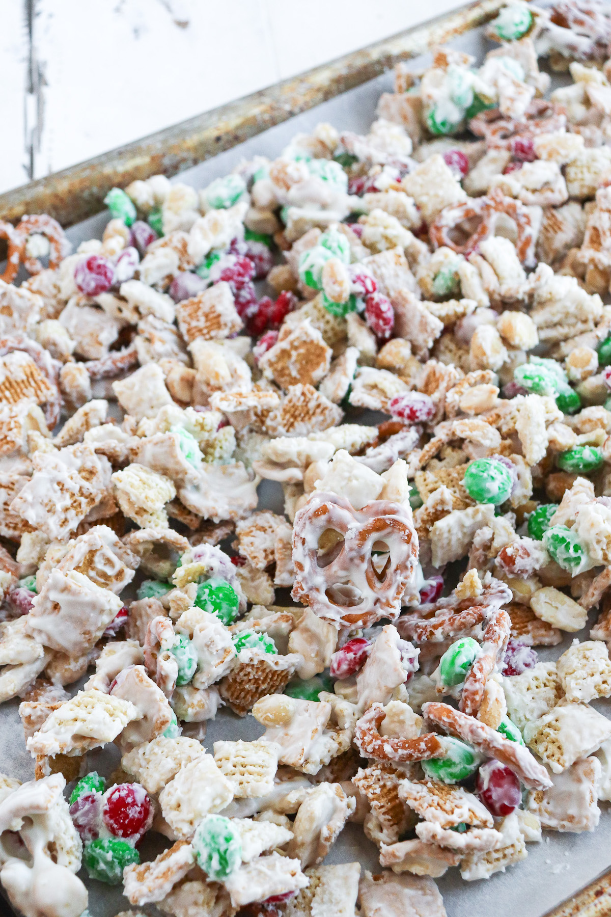 prepared white trash candy snack mix on a large baking sheet lined with parchment paper