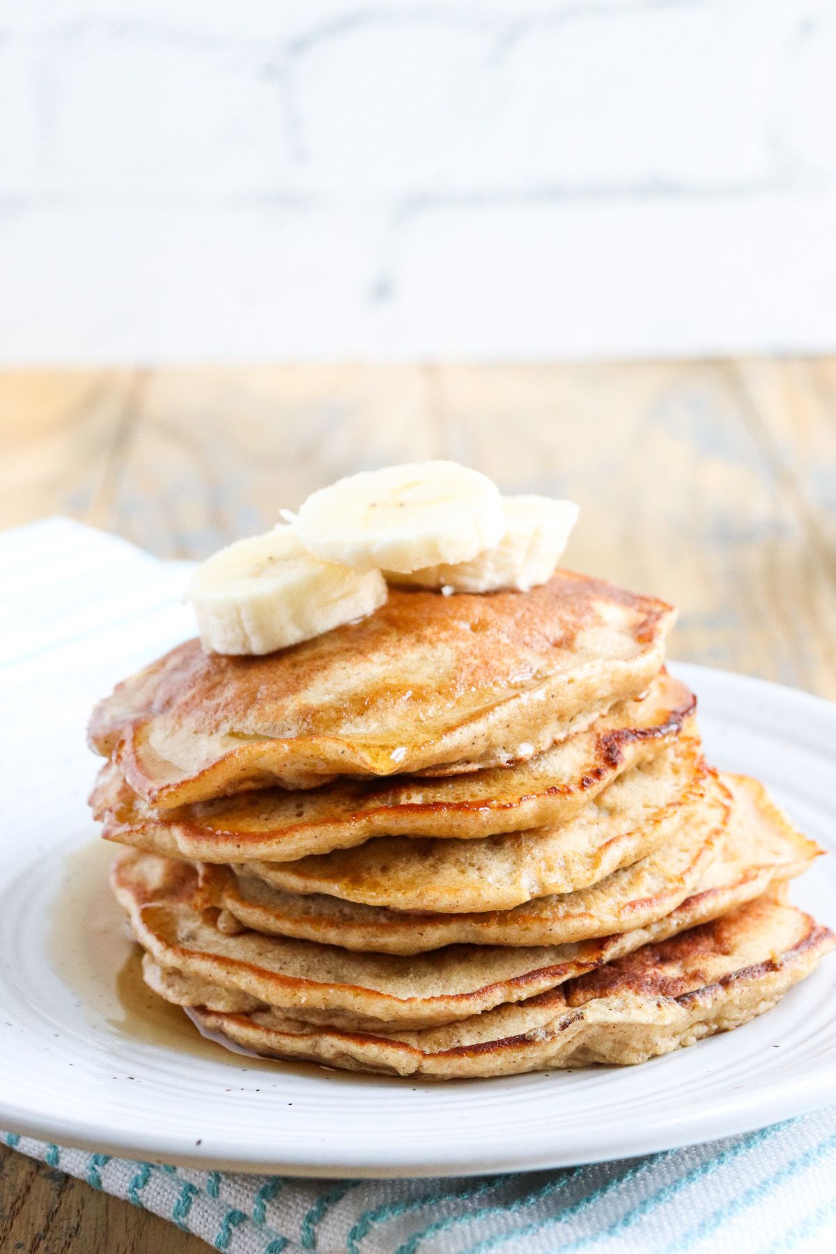 stack of pancakes on white plate with syrup