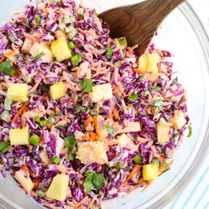 close up of prepared red coleslaw with visible tidbits of pineapple