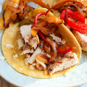 Grilled chicken fajita meat on corn tortilla, topped with fajita veggies and cheese.
