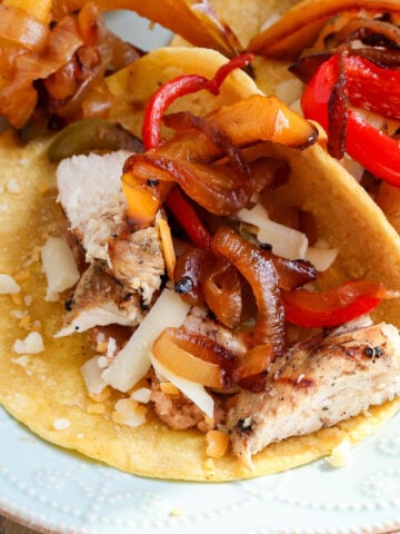 Grilled chicken fajita meat on corn tortilla, topped with fajita veggies and cheese.
