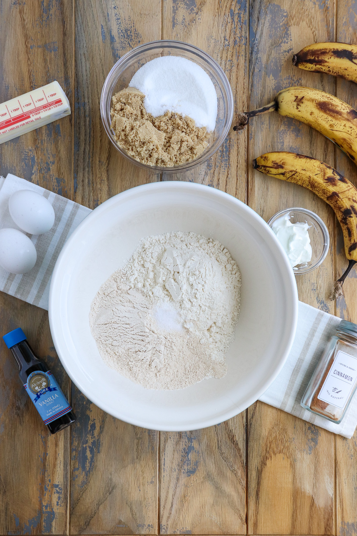 ingredient shot for banana bread - bananas, sugar, cinnamon, sour cream, eggs, butter and vanilla