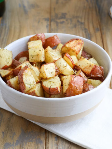 bowl of cooked roasted red potatoes with golden brown spots and visible rosemary