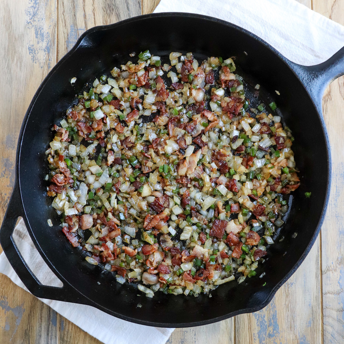 cast iron skillet of cooked bacon, jalapeno and onion