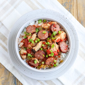 bowl of rice topped with a easy sausage chicken jambalaya and green onions