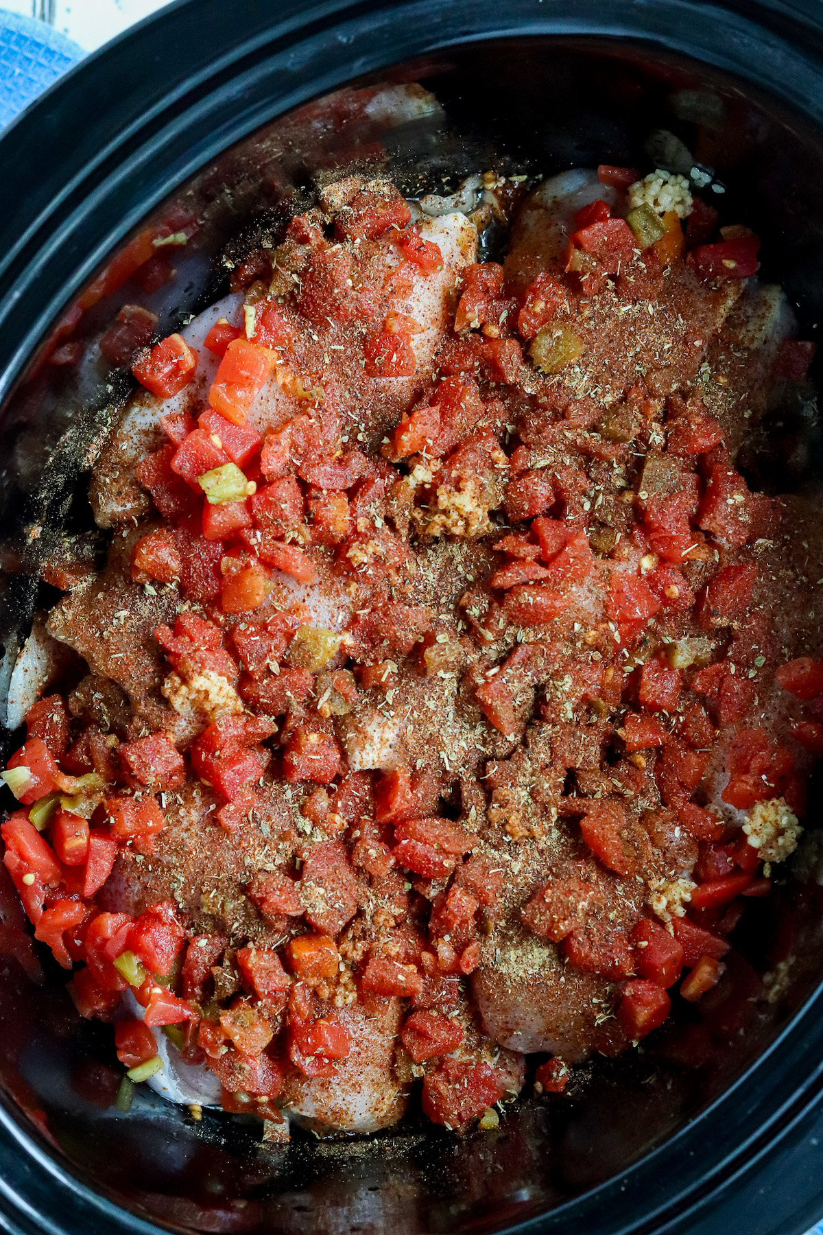 chicken thighs in crockpot topped with Rotel and dried Mexican spices