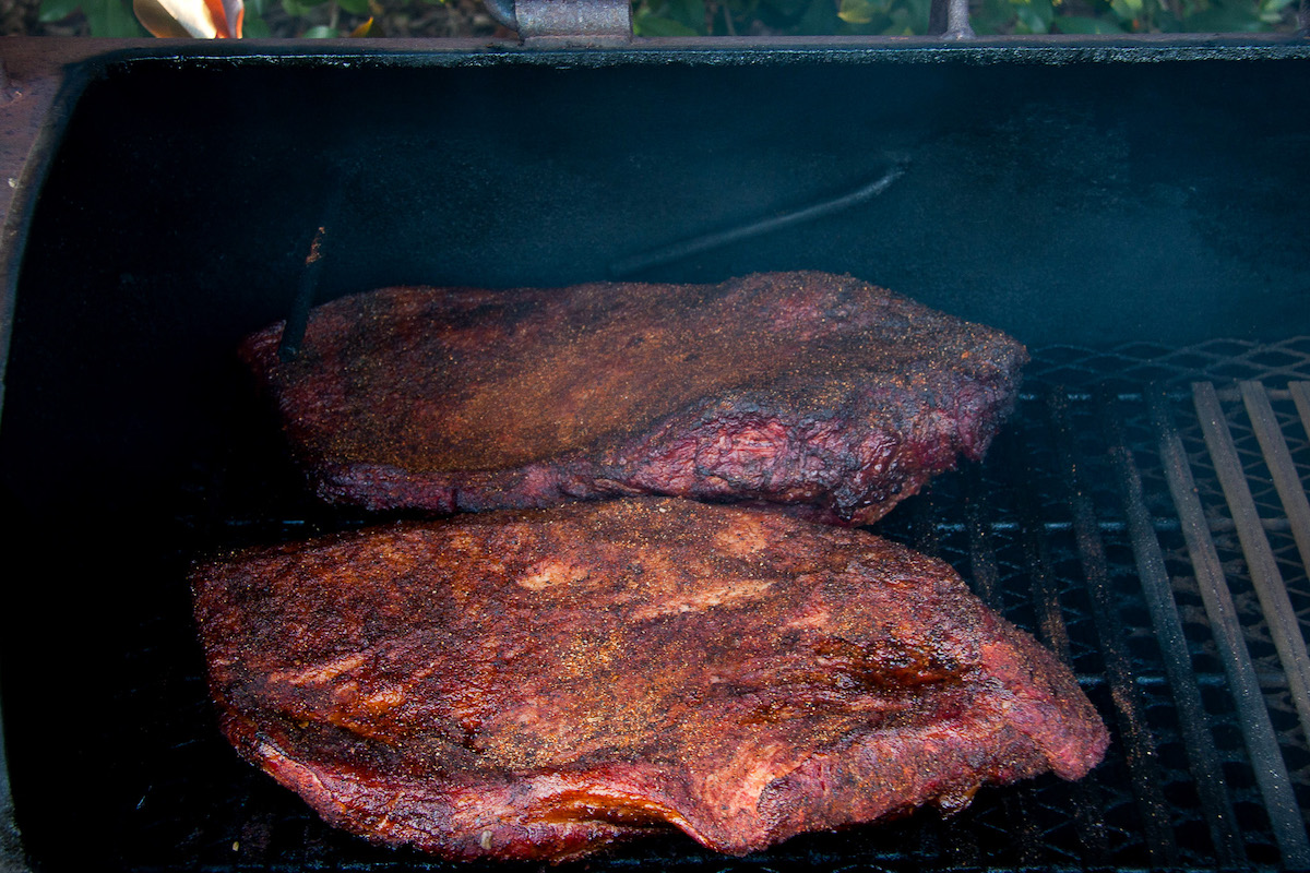 two briskets cooking in a smoker