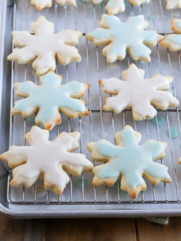 snowflake shaped sugar cookies decorate with sugar cookie icing in light blue and white