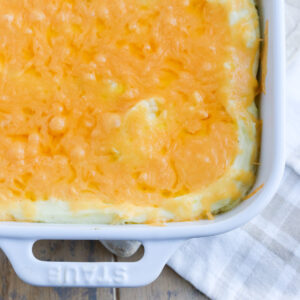 bubbly cheddar cheese over loaded mashed potatoes in a white casserole dish