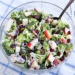 glass bowl of prepared broccoli salad with apples, cranberries and pepitas. Light amount of dressing.