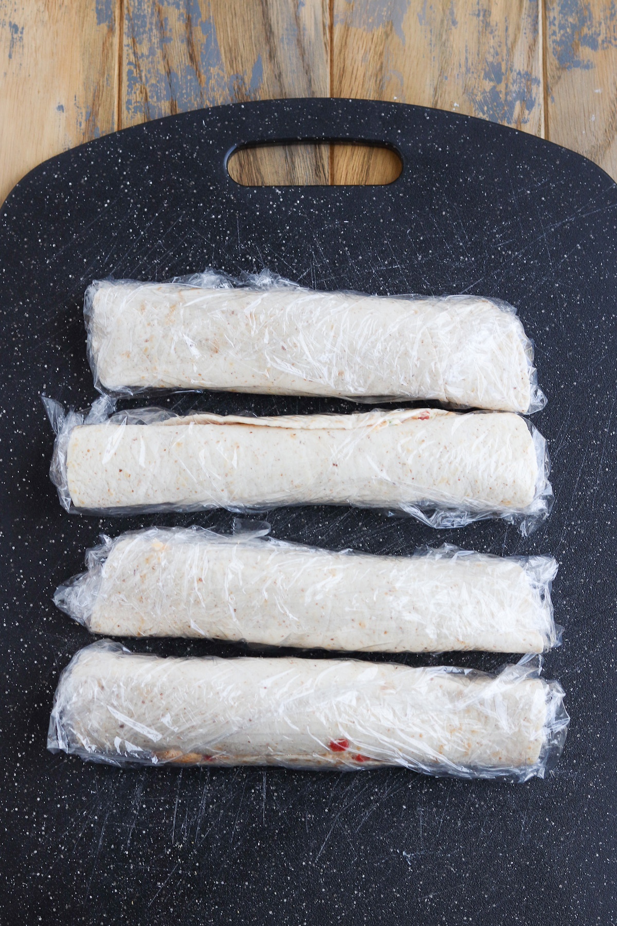 rolled up tortillas in plastic wrap