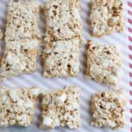 squares of Rice Krispie treats on parchment paper with visible pieces of Golden Grahams and marshmallows