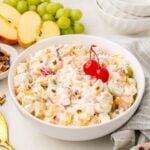serving bowl of prepared ambrosia salad with cherries, coconut and pecan topping