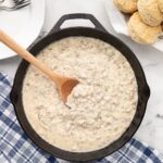 cast iron skillet of jalapeno sausage gravy next to fresh biscuits
