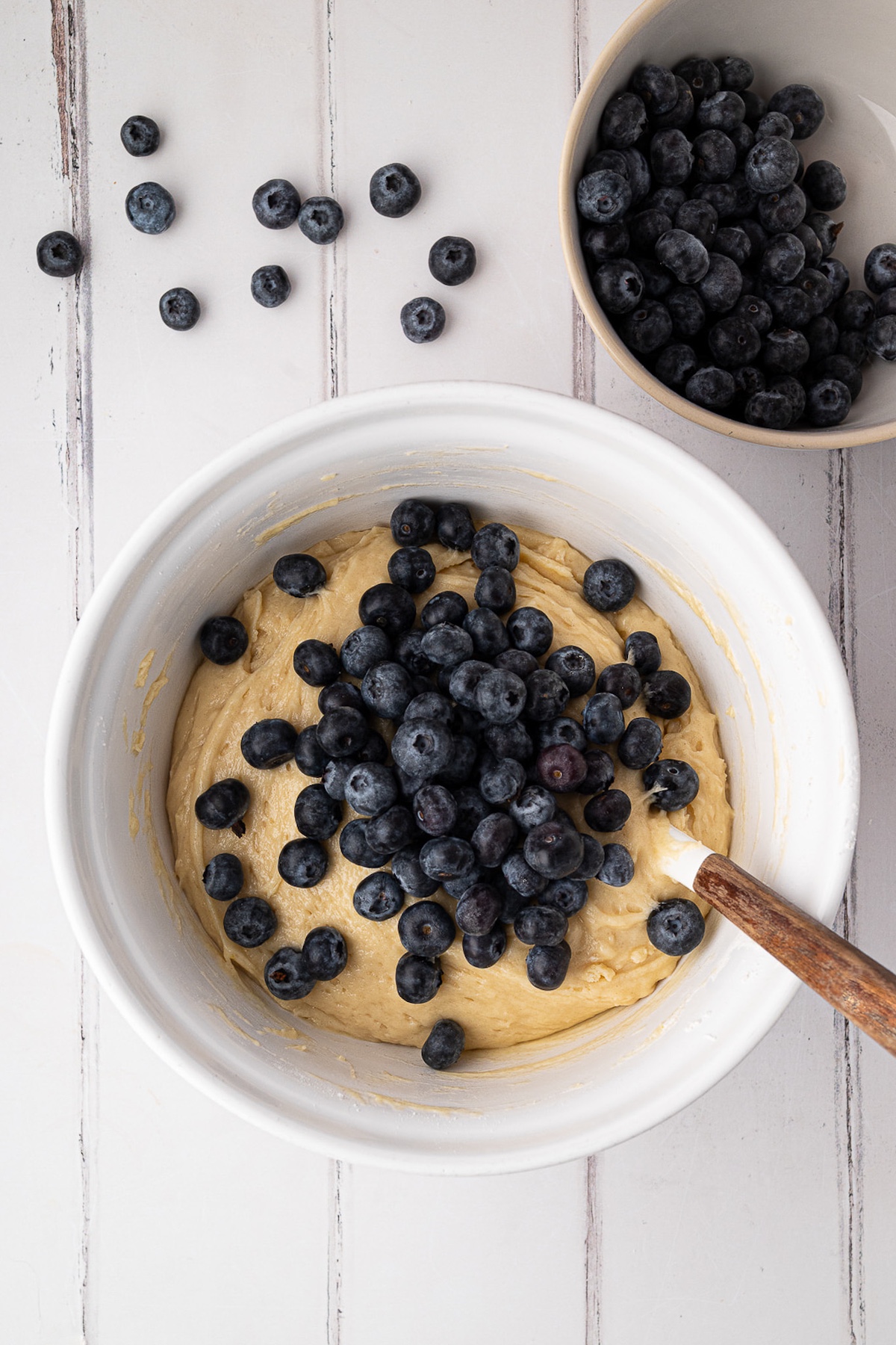folding blueberries into batter in mixing bowl