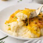 closeup of serving of cheesy mashed potato casserole garnished with green onions