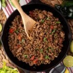 beef taco meat in skillet with visible tomato and cilantro garnish