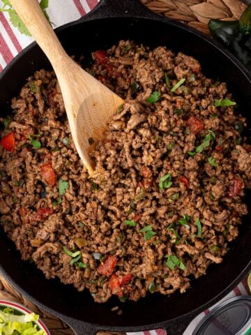 beef taco meat in skillet with visible tomato and cilantro garnish