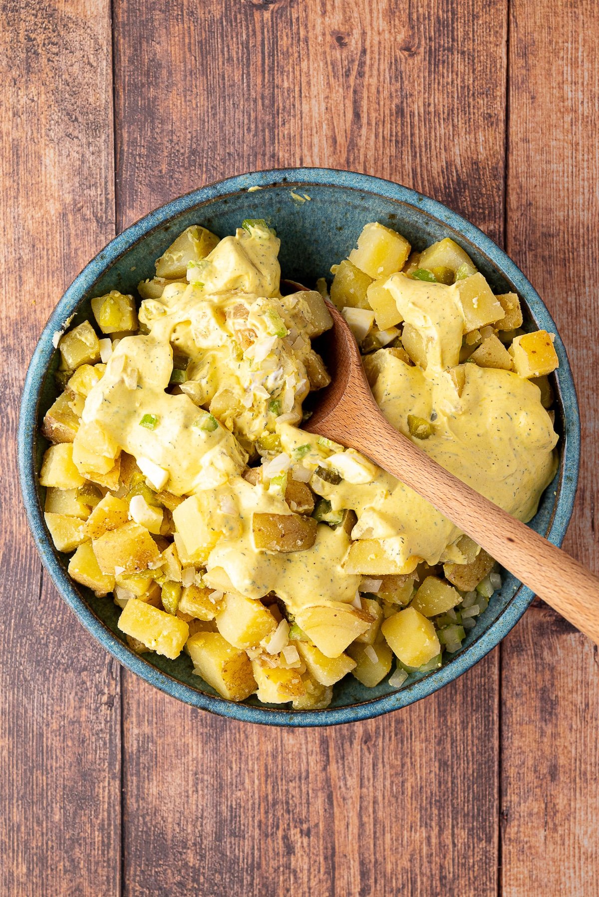 mixing ingredients for potato salad in bowl