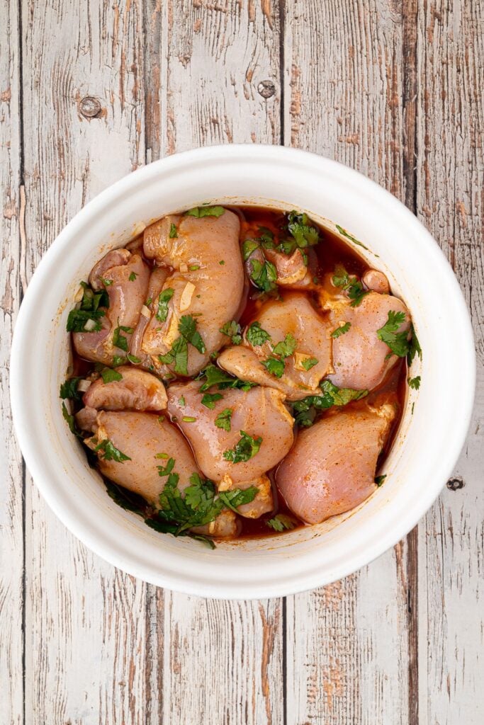 chicken thighs soaking in cilantro and lime marinade in a bowl