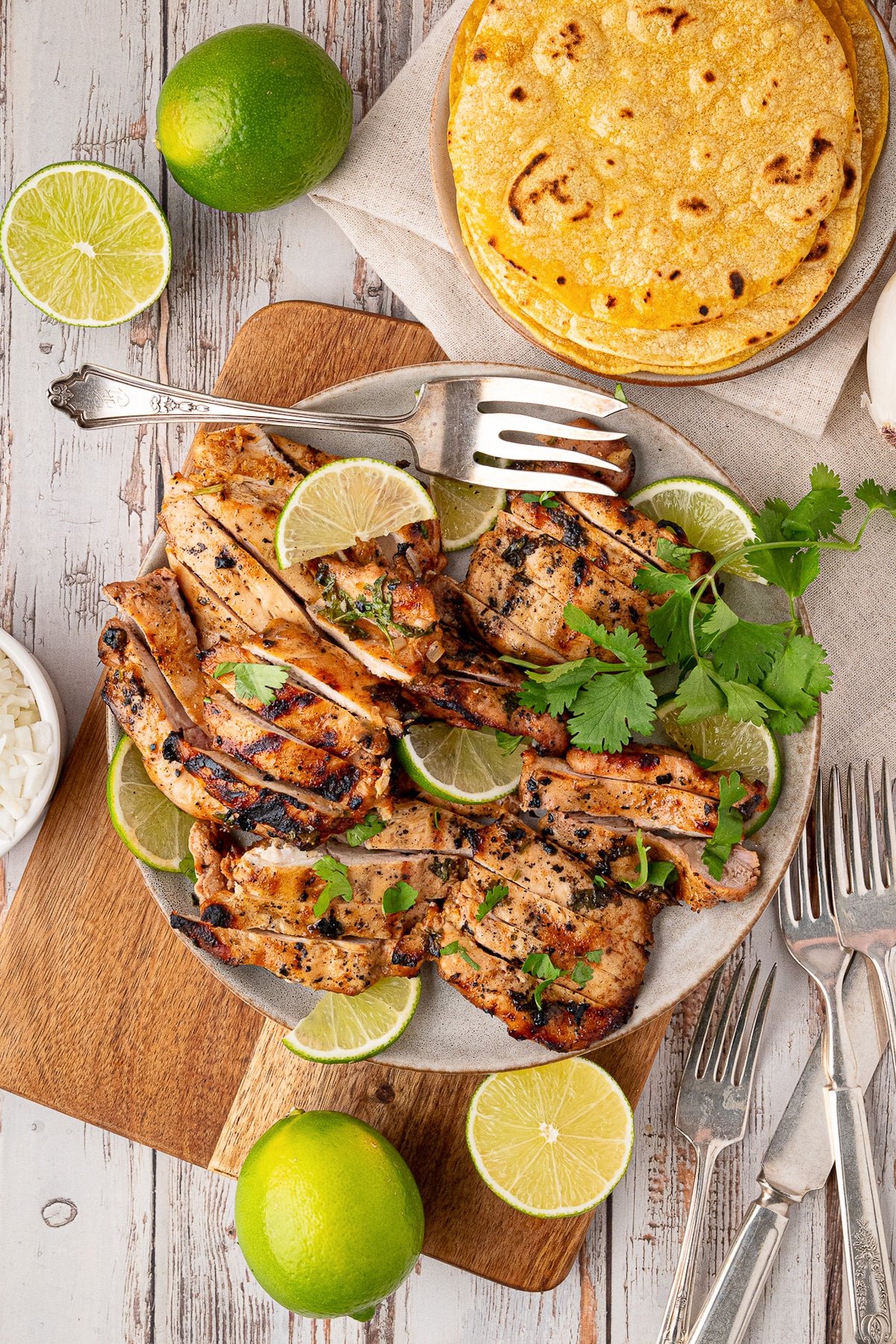 sliced grilled chicken thighs with tortillas, cilantro and lime