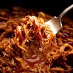 juicy shredded bbq chicken on a fork over crock pot