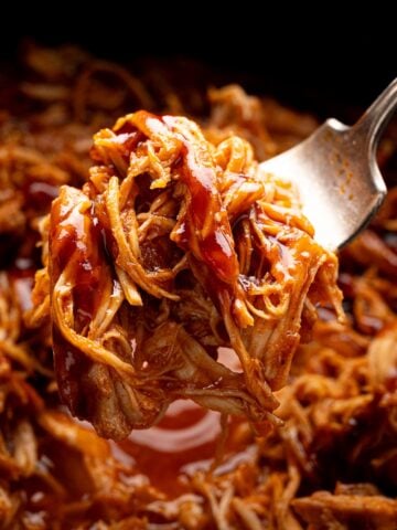 juicy shredded bbq chicken on a fork over crock pot