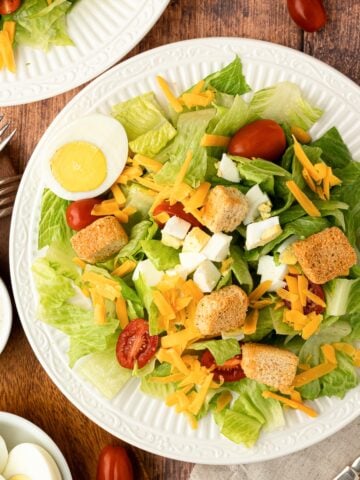 plated Texas Roadhouse Copycat Salad on white plate with ranch, croutons, eggs, tomatoes and lettuce