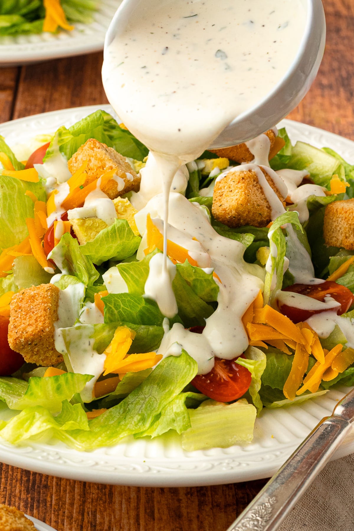 pouring buttermilk ranch dressing over roadhouse salad