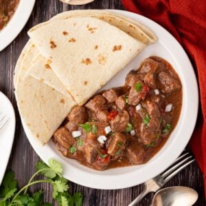 plate of cooked Texas style carne guisada with flour tortillas