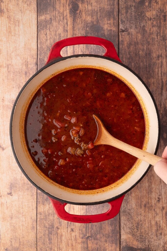 adding tomatoes and liquid to dutch oven for Texas Chili