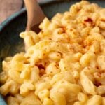 A closeup shot of creamy macaroni and cheese, topped with paprika.