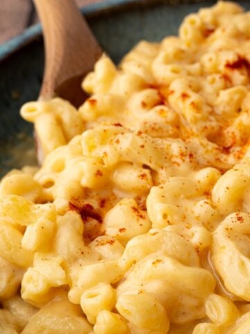A closeup shot of creamy macaroni and cheese, topped with paprika.