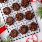 Batch of baked Chocolate Peppermint Cookies on a wire rack garnished with peppermint candy canes and Christmas decor.