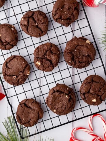 Batch of baked Chocolate Peppermint Cookies on a wire rack garnished with peppermint candy canes and Christmas decor.