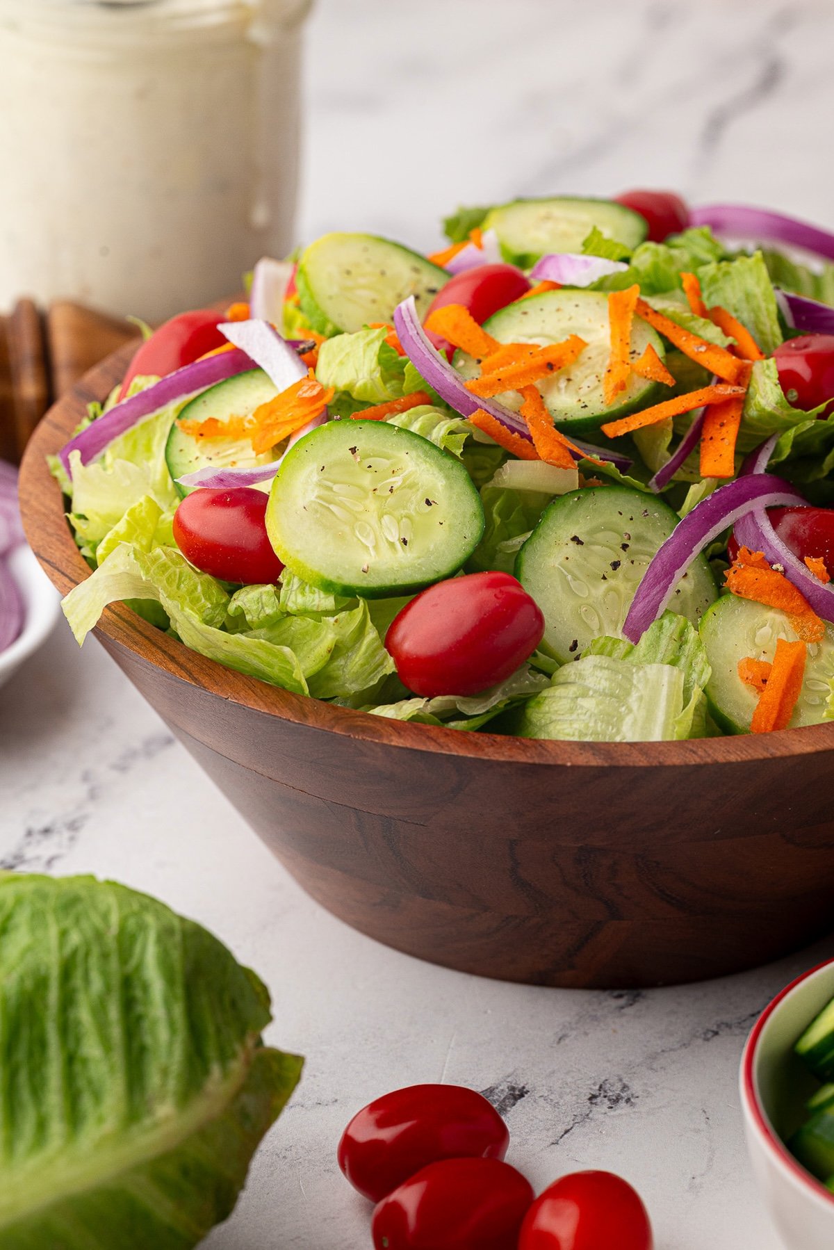 A wooden bowl full of a colorful house salad.
