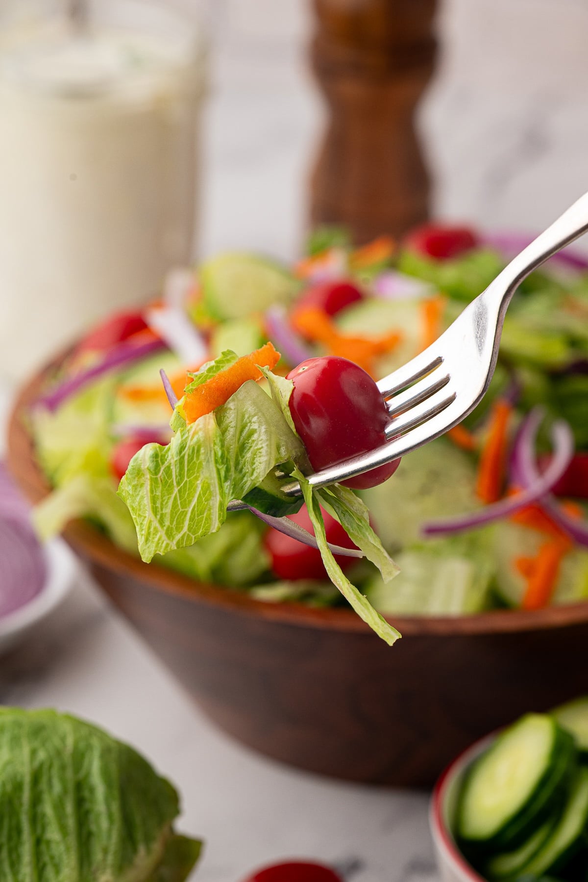A bite of tomato and crisp lettuce on a fork.