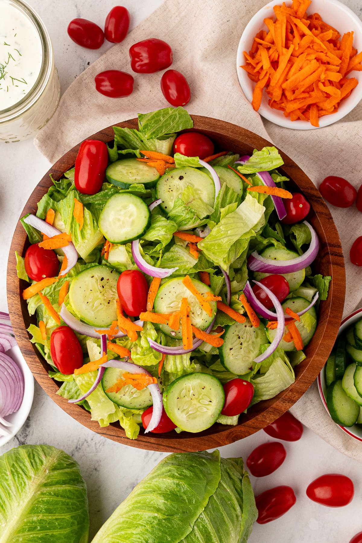 Overhead view showing the salad and ingredients, romaine lettuce, cherry tomatoes, carrots, onions and homemade ranch dressing.