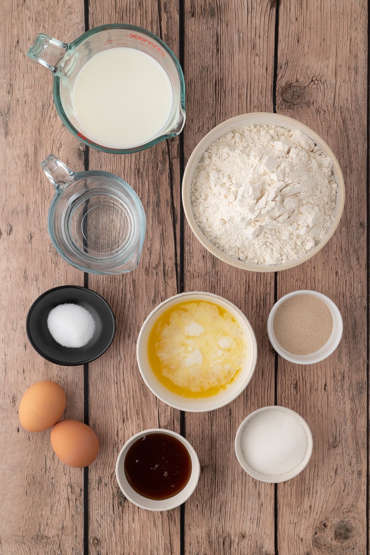 Ingredients pictured for making Texas Roadhouse Rolls at home including milk, yeast, flour, honey, sugar, eggs and salt.