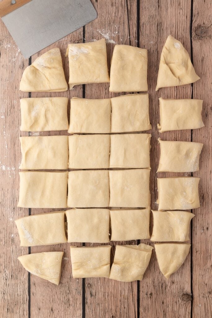 Cutting the dough into individual rolls using a pastry bench scraper.