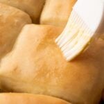 Brushing the tops of the Texas Roadhouse Copycat Rolls with melted butter.