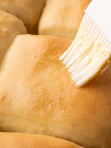 Brushing the tops of the Texas Roadhouse Copycat Rolls with melted butter.