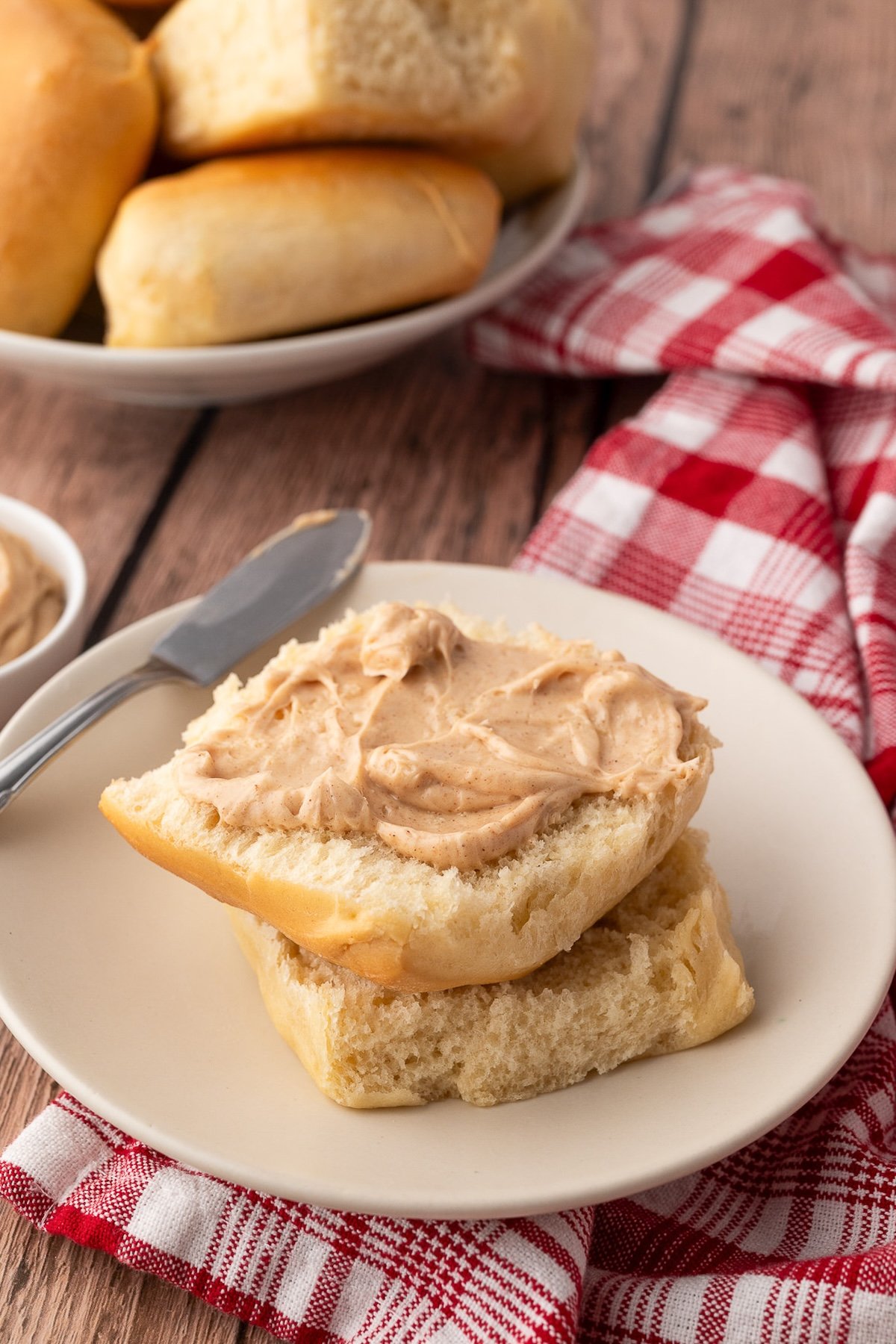 A baked dinner roll cut in half and topped with cinnamon honey butter.