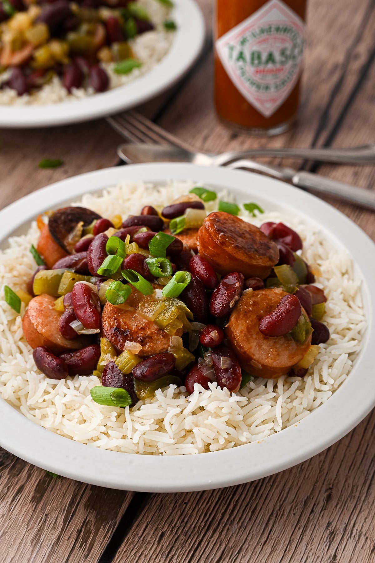 Side angle of a bowl of quick red beans and rice showing the ratio of beans to rice, served with a bottle of Tabasco sauce in the background.