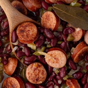 Overhead view of a finished skillet of red beans and rice with visible bay leaf and steam rising.