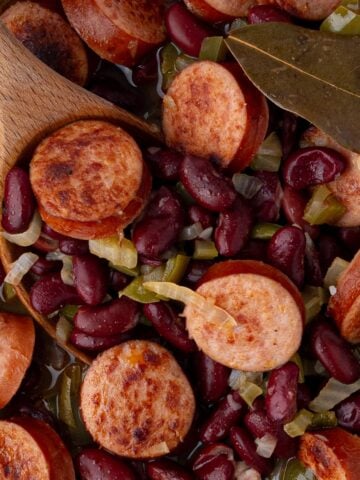 Overhead view of a finished skillet of red beans and rice with visible bay leaf and steam rising.