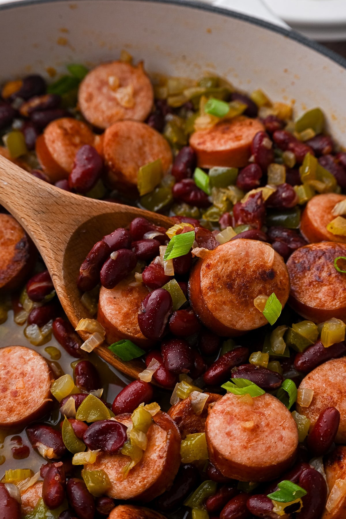 Red beans and sausage mixture simmering in a skillet to thicken the sauce without mashing the beans.